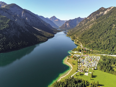Aerial view of Plansee lake surrounded by lush green mountains dense forests and a lakeside campsite in Reutte District Tyrol Austria. Aerial view of Plansee lake surrounded by lush green mountains dense forests and a lakeside campsite in Reutte District Tyrol Austria.