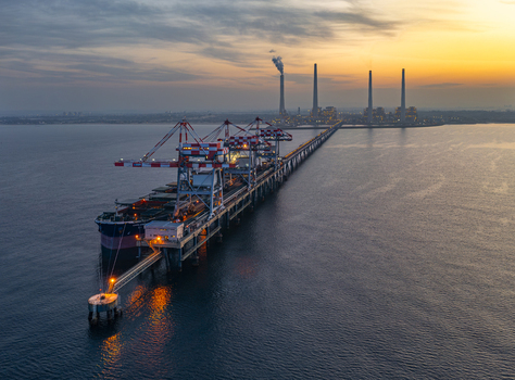 Aerial view of a large cargo ship docked at the pier of the Orot Rabin Power Plant during a golden sunset with industrial chimneys and calm sea waters in Hadera Haifa District Israel. Aerial view of a large cargo ship docked at the pier of the Orot Rabin Power Plant during a golden sunset with industrial chimneys and calm sea waters in Hadera Haifa District Israel.