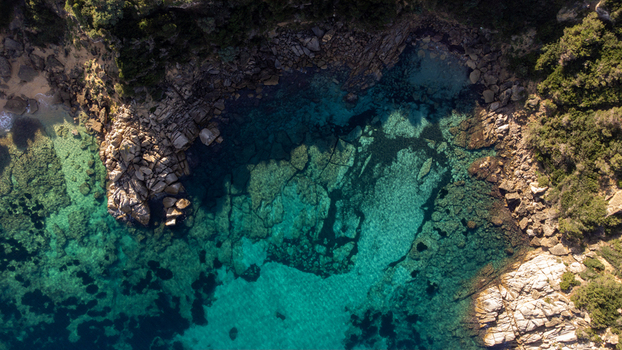 Aerial view of the rocky coastline and turquoise waters of Capo Testa featuring clear seabed rugged cliffs and Mediterranean vegetation in Santa Teresa Gallura Sardinia Italy. Aerial view of the rocky coastline and turquoise waters of Capo Testa featuring clear seabed rugged cliffs and Mediterranean vegetation in Santa Teresa Gallura Sardinia Italy.