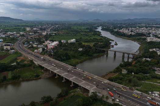 Aerial view of a highway bridge spanning a river with surrounding green fields and urban development in Karad Maharashtra India.