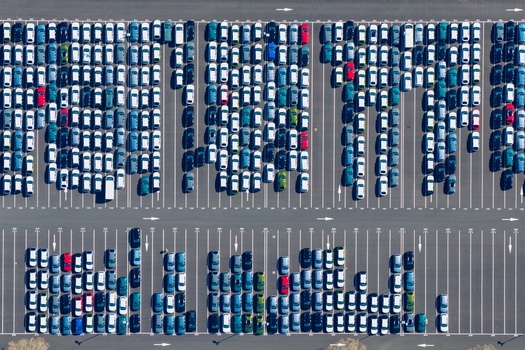 Aerial view of tightly packed cars forming a grid of color and texture with rows of white lines creating stark contrast against the asphalt Sausheim Grand Est France.