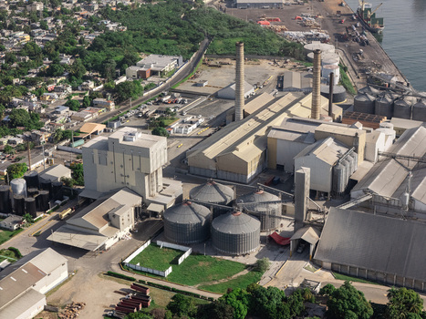 Aerial view of an industrial complex featuring large storage silos factory buildings with tall chimneys and port infrastructure in Bajos de Haina San Cristobal Provinc Dominican Republic.