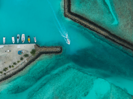 Aerial view of boats nestled along the shore juxtaposed against the turquoise waters and sharp geometric lines of the breakwaters Vashafaru Island Maldives. Aerial view of boats nestled along the shore juxtaposed against the turquoise waters and sharp geometric lines of the breakwaters Vashafaru Island Maldives.