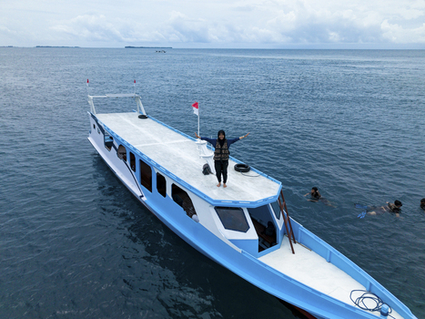Aerial view of a boat with a person standing on top with swimmers nearby Cemara Kecil Snorkeling Spot Karimunjawa Central Java Indonesia.
