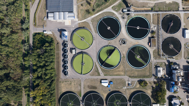 Aerial view of Klarwerk Karlsruhe wastewater treatment plant showing circular sedimentation tanks industrial infrastructure and forest in Karlsruhe Baden Wurttemberg Germany.