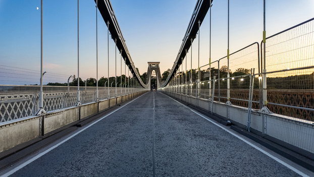 View of Clifton Suspension Bridge with its iconic stone tower and suspension cables under a clear twilight sky Bristol United Kingdom.