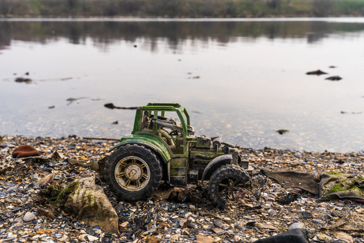 View of a weathered toy tractor abandoned on the pebbly muddy shore of Lake Varna Varna Bulgaria. View of a weathered toy tractor abandoned on the pebbly muddy shore of Lake Varna Varna Bulgaria.