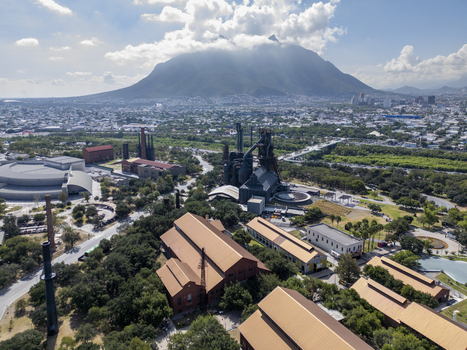 Aerial view of the historic Fundidora Park featuring industrial architecture lush green spaces and the iconic Cerro de la Silla mountain in the background in Monterrey Nuevo Leon Mexico. Aerial view of the historic Fundidora Park featuring industrial architecture lush green spaces and the iconic Cerro de la Silla mountain in the background in Monterrey Nuevo Leon Mexico.