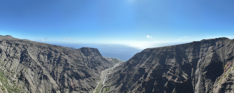 Aerial view of the rugged volcanic landscape and deep canyon of La Gomera leading to the Atlantic Ocean under a clear blue sky in Santa Cruz de Tenerife Canary Islands Spain.
