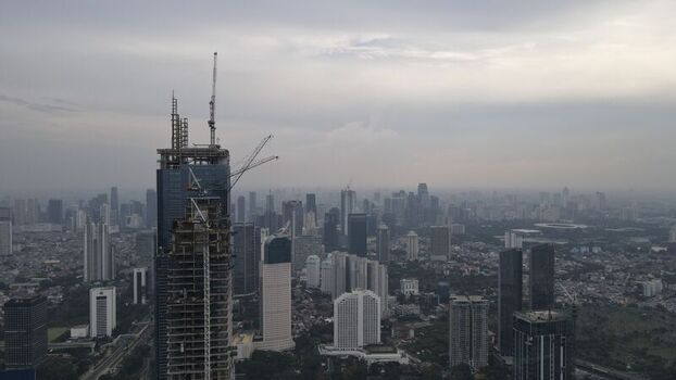 Kecamatan Menteng Indonesia 03 December 2021 Aerial view of the Jakarta Pusat skyline featuring a prominent skyscraper under construction with cranes against a cloudy sky. Kecamatan Menteng Indonesia 03 December 2021 Aerial view of the Jakarta Pusat skyline featuring a prominent skyscraper under construction with cranes against a cloudy sky.