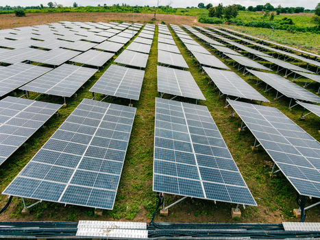 Aerial view of a large solar farm with rows of photovoltaic panels installed in a grassy field in Ogun State Nigeria.