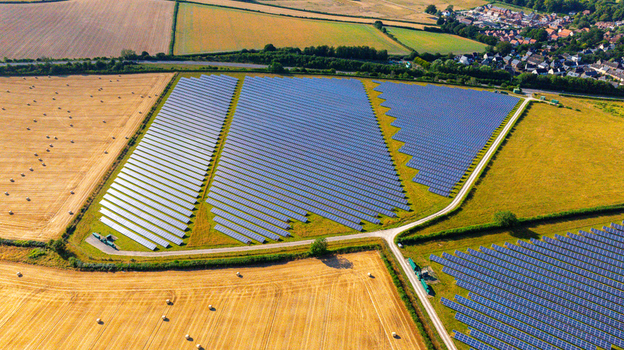 Aerial view of a large solar farm with rows of photovoltaic panels set in rural fields near a small village in Dorset England United Kingdom. Aerial view of a large solar farm with rows of photovoltaic panels set in rural fields near a small village in Dorset England United Kingdom.
