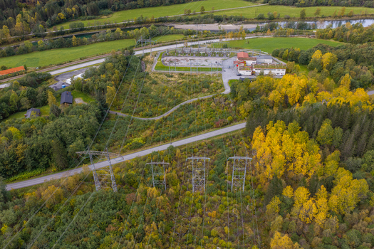 Aerial view of an electrical substation in a forested landscape with autumn foliage power lines and a river nearby in Andalsnes More og Romsdal Norway. Aerial view of an electrical substation in a forested landscape with autumn foliage power lines and a river nearby in Andalsnes More og Romsdal Norway.