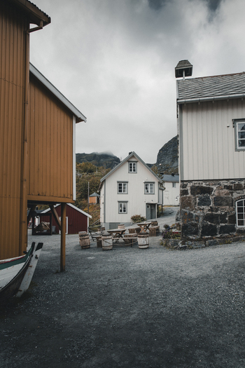 Nusfjord Nordland Norway 07 September 2022 View of the historic fishing village of Nusfjord with its traditional wooden buildings gravel paths and rustic outdoor seating under an overcast sky. Nusfjord Nordland Norway 07 September 2022 View of the historic fishing village of Nusfjord with its traditional wooden buildings gravel paths and rustic outdoor seating under an overcast sky.