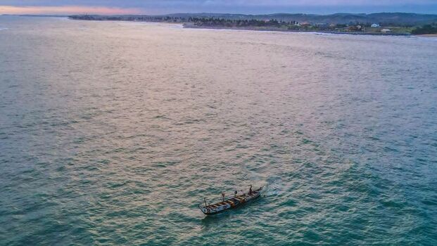 Aerial view of a traditional wooden fishing boat sailing on the calm ocean waters near the coastline of Ghana. Aerial view of a traditional wooden fishing boat sailing on the calm ocean waters near the coastline of Ghana.