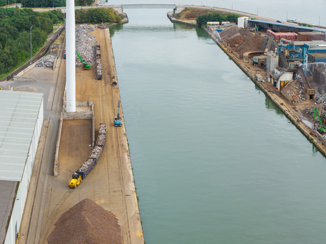 Aerial view of the Haven Genk industrial recycling facility featuring scrap metal piles railway freight logistics and loading equipment along the canal in Genk Vlaanderen Belgium. Aerial view of the Haven Genk industrial recycling facility featuring scrap metal piles railway freight logistics and loading equipment along the canal in Genk Vlaanderen Belgium.