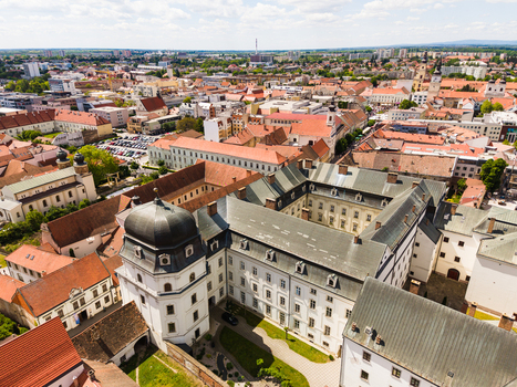 Aerial view of the historic university buildings with a white facade and inner courtyard among red rooftops under a bright sky in Trnava Trnava Region Slovakia. Aerial view of the historic university buildings with a white facade and inner courtyard among red rooftops under a bright sky in Trnava Trnava Region Slovakia.