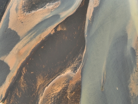 Aerial view of the winding glacial river patterns with dark volcanic sand and sediment deposits flowing through the landscape in Selfoss Sveitarfelagid Arborg Iceland. Aerial view of the winding glacial river patterns with dark volcanic sand and sediment deposits flowing through the landscape in Selfoss Sveitarfelagid Arborg Iceland.