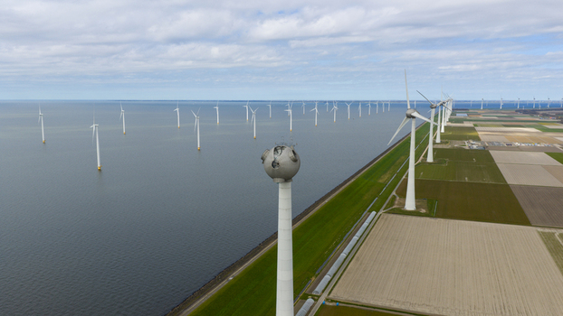 Aerial view of wind turbines installed in the water and along the coastline next to agricultural fields under a cloudy sky in Espel Flevoland Netherlands. Aerial view of wind turbines installed in the water and along the coastline next to agricultural fields under a cloudy sky in Espel Flevoland Netherlands.
