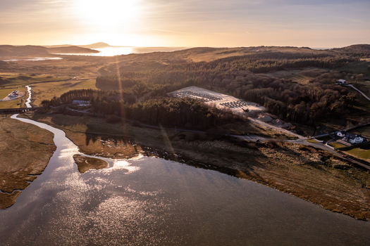 Aerial view of the coastal landscape near Dunfanaghy featuring a winding river dense forest and a parking area illuminated by the golden hour light in Dunfanaghy County Donegal Ireland. Aerial view of the coastal landscape near Dunfanaghy featuring a winding river dense forest and a parking area illuminated by the golden hour light in Dunfanaghy County Donegal Ireland.