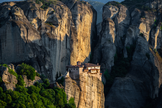 Aerial view of Meteora monastery perched on a towering sandstone rock formation surrounded by lush green trees and dramatic cliffs in Trikala Greece. Aerial view of Meteora monastery perched on a towering sandstone rock formation surrounded by lush green trees and dramatic cliffs in Trikala Greece.