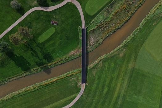 Aerial view of the bridge crossing Cherry Creek surrounded by lush green golf course fairways and walking paths in Denver Colorado United States. Aerial view of the bridge crossing Cherry Creek surrounded by lush green golf course fairways and walking paths in Denver Colorado United States.