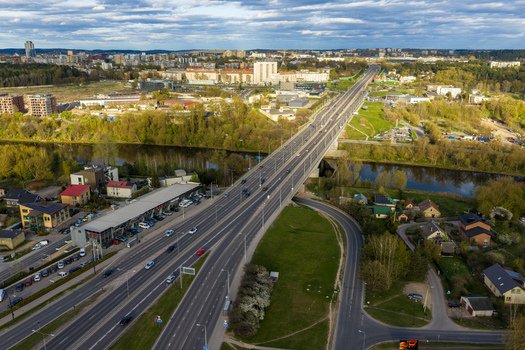 Vilnius Lithuania 01 May 2026 Aerial view of a multi lane bridge spanning the Neris River showing traffic flow surrounding green spaces and the city skyline in the distance. Vilnius Lithuania 01 May 2026 Aerial view of a multi lane bridge spanning the Neris River showing traffic flow surrounding green spaces and the city skyline in the distance.