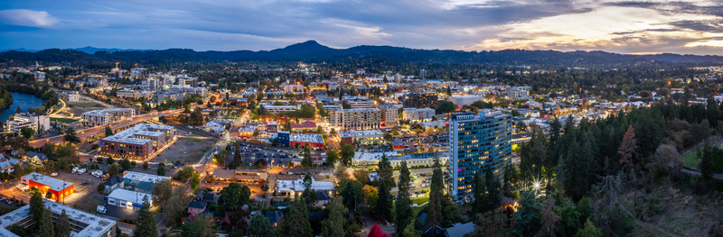 Aerial view of Eugene Oregon showing downtown buildings residential neighborhoods urban growth streets and surrounding hills at dusk. Aerial view of Eugene Oregon showing downtown buildings residential neighborhoods urban growth streets and surrounding hills at dusk.