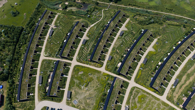 Aerial view of modern earth sheltered houses with green roofs arranged in rows within a sustainable residential neighborhood in Almere Flevoland Netherlands. Aerial view of modern earth sheltered houses with green roofs arranged in rows within a sustainable residential neighborhood in Almere Flevoland Netherlands.
