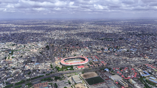 Aerial view of the National Stadium Surulere Lagos surrounded by the dense urban sprawl and residential neighborhoods under a cloudy sky in Lagos Lagos Nigeria.
