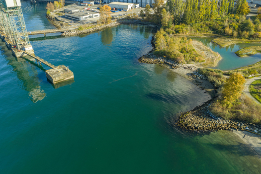 Aerial view of Vancouver Harbour featuring a concrete pier extending into deep blue water surrounded by lush autumn trees and rocky shoreline in Vancouver British Columbia Canada. Aerial view of Vancouver Harbour featuring a concrete pier extending into deep blue water surrounded by lush autumn trees and rocky shoreline in Vancouver British Columbia Canada.