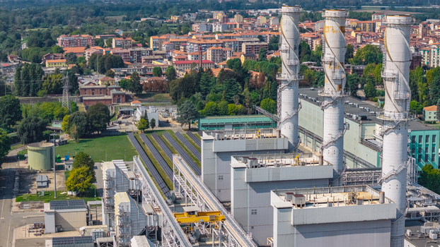 Aerial view of the Chivasso combined cycle power plant featuring three tall exhaust stacks and rows of photovoltaic solar panels near the town of Chivasso Piedmont Italy. Aerial view of the Chivasso combined cycle power plant featuring three tall exhaust stacks and rows of photovoltaic solar panels near the town of Chivasso Piedmont Italy.