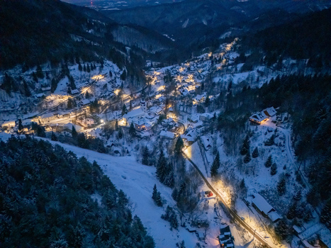 Aerial view of the historic village of Spania Dolina nestled in a snowy valley at night with glowing lights and dark mountains in Spania Dolina Banska Bystrica Region Slovakia. Aerial view of the historic village of Spania Dolina nestled in a snowy valley at night with glowing lights and dark mountains in Spania Dolina Banska Bystrica Region Slovakia.