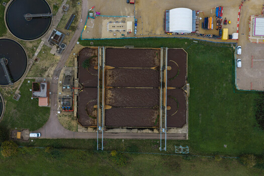 Aerial view of a wastewater treatment plant with circular sedimentation tanks and rectangular treatment basins surrounded by green grass in the United Kingdom. Aerial view of a wastewater treatment plant with circular sedimentation tanks and rectangular treatment basins surrounded by green grass in the United Kingdom.