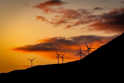 View of wind turbines silhouetted against a vibrant orange sunset sky on a hill in Sandpatch Western Australia Australia. View of wind turbines silhouetted against a vibrant orange sunset sky on a hill in Sandpatch Western Australia Australia.