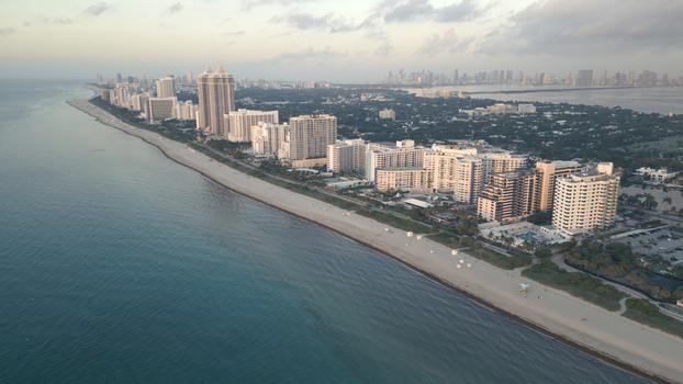 Aerial view of Miami Beach coastline featuring high rise hotels and condominiums along the sandy shore in Miami Beach Florida United States. Aerial view of Miami Beach coastline featuring high rise hotels and condominiums along the sandy shore in Miami Beach Florida United States.
