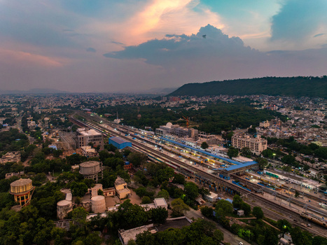 Aerial view of Udaipur Railway Station with surrounding urban landscape lush greenery and distant hills under a sunset sky in Udaipur Rajasthan India. Aerial view of Udaipur Railway Station with surrounding urban landscape lush greenery and distant hills under a sunset sky in Udaipur Rajasthan India.