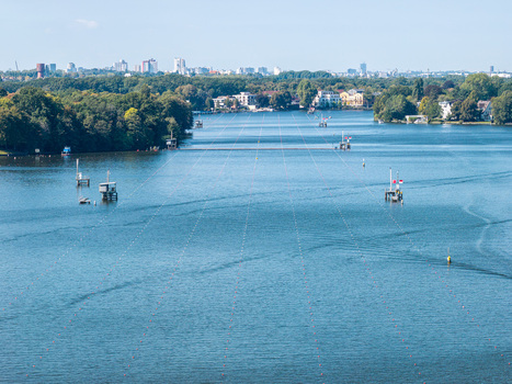 Aerial view of Berlin Grunau Regatta Course with its long lanes marked by buoys on the Dahme river surrounded by lush trees and distant urban skyline in Berlin Berlin Germany. Aerial view of Berlin Grunau Regatta Course with its long lanes marked by buoys on the Dahme river surrounded by lush trees and distant urban skyline in Berlin Berlin Germany.