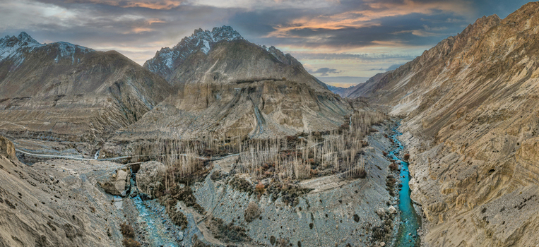 Aerial view of the rugged Chapursan Valley where the azure river winds through the stark mountainous terrain under a pastel sky Hunza Nagar Gilgit Pakistan. Aerial view of the rugged Chapursan Valley where the azure river winds through the stark mountainous terrain under a pastel sky Hunza Nagar Gilgit Pakistan.