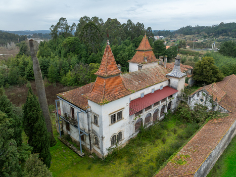 Aerial view of the abandoned Ruinas Quinta da Zombaria with its distinctive red tiled towers and overgrown grounds surrounded by lush forest in Antuzede e Vil de Matos Coimbra Portugal.