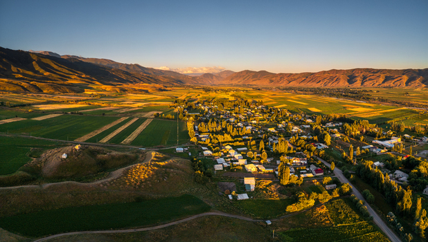 Aerial view of the Chon Kemin valley village with agricultural fields and rolling mountains under the golden light of sunset in Kaindy Chuy Province Kyrgyzstan.