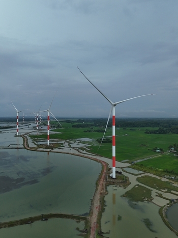 Aerial view of the Khurushkul wind power plant with red and white turbines set amidst lush green fields and coastal wetlands in Cox s Bazar Chittagong Division Bangladesh. Aerial view of the Khurushkul wind power plant with red and white turbines set amidst lush green fields and coastal wetlands in Cox s Bazar Chittagong Division Bangladesh.