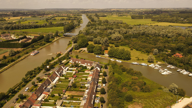 Aerial view of the canal marina with docked boats and residential houses with gardens surrounded by lush greenery in Saint Omer Hauts de France France. Aerial view of the canal marina with docked boats and residential houses with gardens surrounded by lush greenery in Saint Omer Hauts de France France.