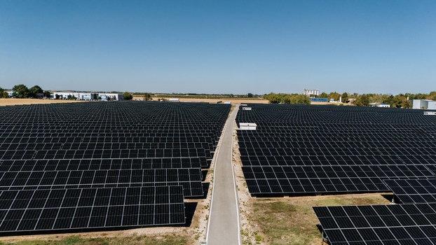 Aerial view of a large solar farm with rows of photovoltaic panels and a central access path under a clear blue sky in Temerin Vojvodina Serbia. Aerial view of a large solar farm with rows of photovoltaic panels and a central access path under a clear blue sky in Temerin Vojvodina Serbia.