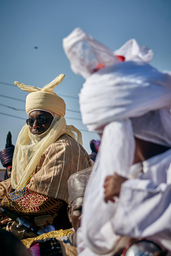 Zaria City Nigeria 22 March 2026 View of a regal figure in warm cream traditional attire and dark sunglasses a striking contrast against the bright white of a companion and the crisp blue sky. Zaria City Nigeria 22 March 2026 View of a regal figure in warm cream traditional attire and dark sunglasses a striking contrast against the bright white of a companion and the crisp blue sky.