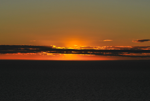 View of a vibrant sunset over the Atlantic Ocean with dark clouds on the horizon and golden light reflecting on the water near Puerto Piramides Puerto Madryn Chubut Argentina. View of a vibrant sunset over the Atlantic Ocean with dark clouds on the horizon and golden light reflecting on the water near Puerto Piramides Puerto Madryn Chubut Argentina.