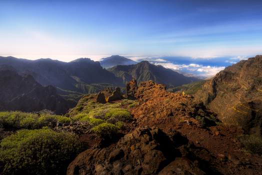 View of the rugged volcanic peaks and lush green slopes from Mirador del Espigon del Roque under a clear blue sky in El Paso Canarias Spain. View of the rugged volcanic peaks and lush green slopes from Mirador del Espigon del Roque under a clear blue sky in El Paso Canarias Spain.