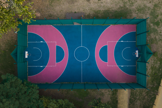 Aerial view of the basketball court at Bentworth Open Space with a vibrant blue and pink surface surrounded by a green fence in London England United Kingdom. Aerial view of the basketball court at Bentworth Open Space with a vibrant blue and pink surface surrounded by a green fence in London England United Kingdom.