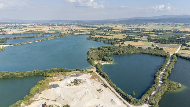 Aerial view of the Extraccion de aridos Lima S.L. gravel extraction site with water filled pits sand piles and rural landscape in Vilarino das Poldras Ourense Spain. Aerial view of the Extraccion de aridos Lima S.L. gravel extraction site with water filled pits sand piles and rural landscape in Vilarino das Poldras Ourense Spain.