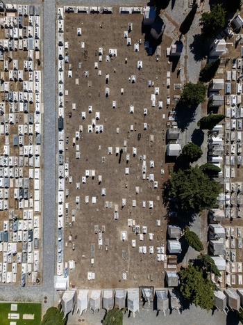 Aerial view of the cemetery with rows of white tombstones stone graves and scattered trees in Evora Evora District Portugal. Aerial view of the cemetery with rows of white tombstones stone graves and scattered trees in Evora Evora District Portugal.